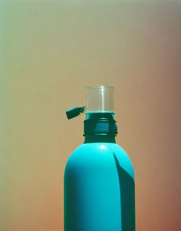 Turquoise Water Bottle with Open Spout and Transparent Cup on Warm Background