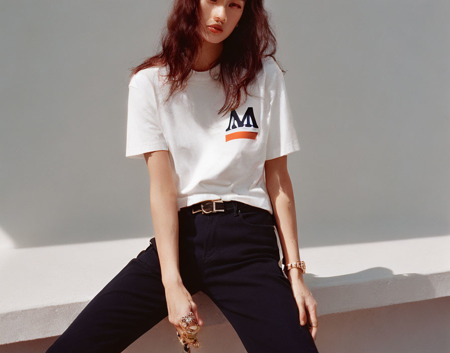 Confident woman in white logo t-shirt and dark pants with accessories