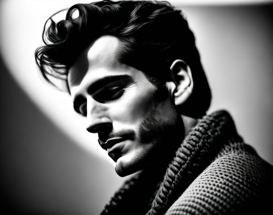 Monochrome side profile of man with styled hair and thick beard in textured high-neck sweater