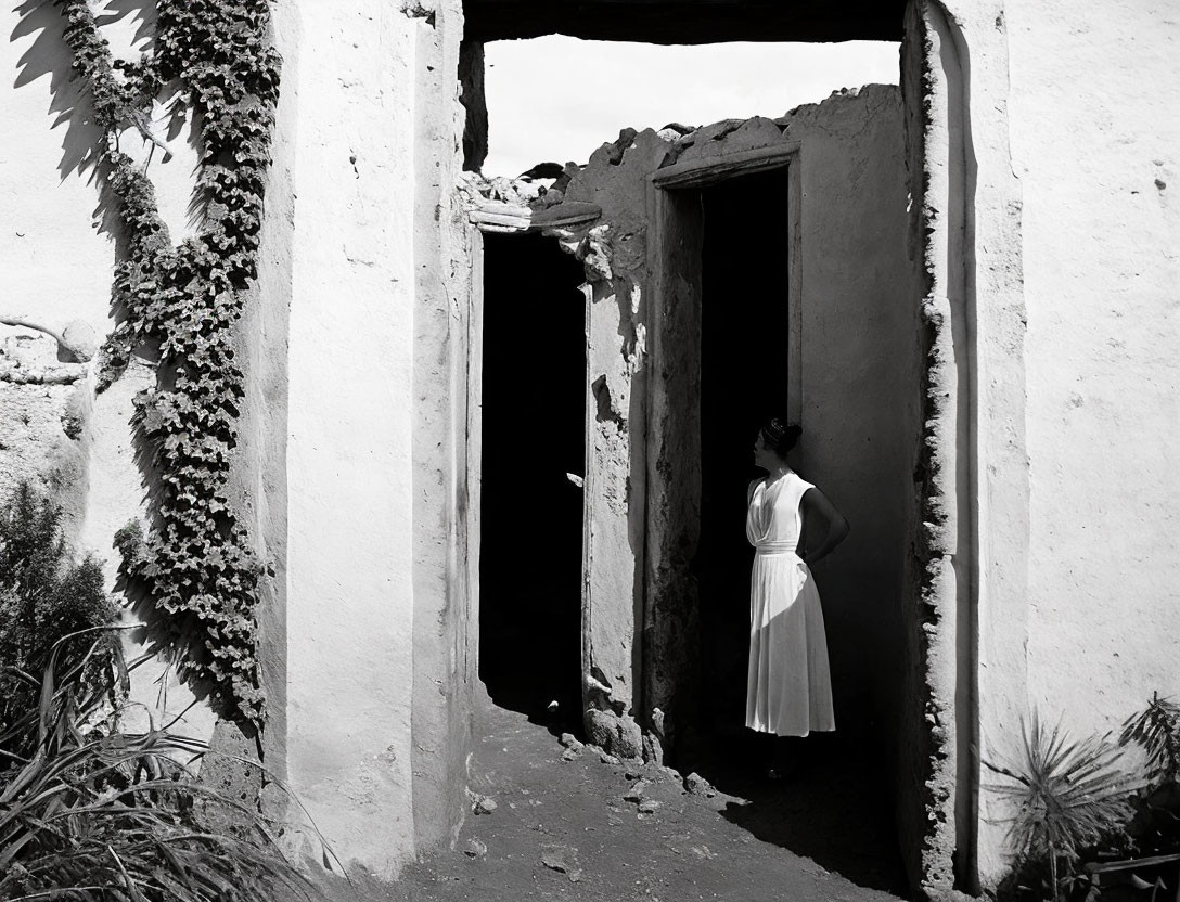 Person in white dress at threshold of dilapidated doorway in abandoned building