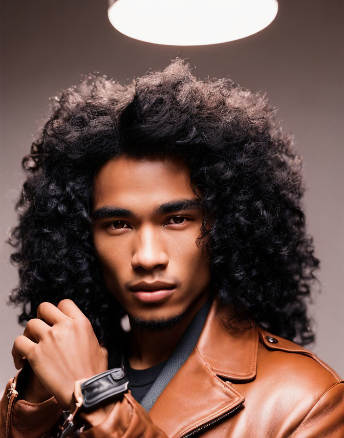 Curly-Haired Man in Brown Leather Jacket Under Warm Light