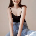 Smiling woman with dark hair in black top and blue skirt sitting portrait