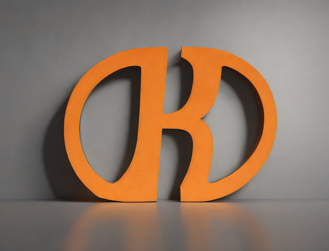 Circular orange logo with cutout letter K on gray background with shadows