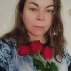 Young woman with fair skin and rosy cheeks holding flowers in blue dress