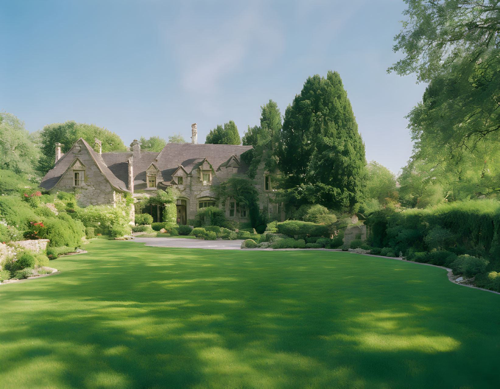 Manicured lawn and elegant stone house with lush greenery