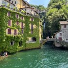 Hillside terraced houses and old stone bridge over green river