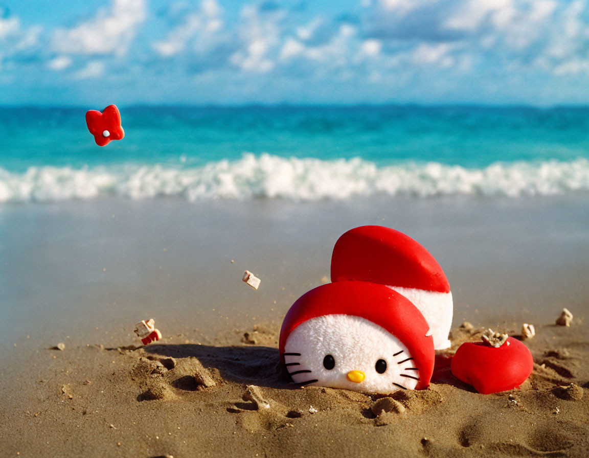 Hello Kitty Figure in Red Hood on Sandy Beach with Blue Skies