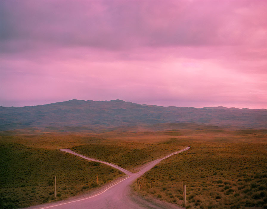 Winding Road in Hilly Landscape under Pink Sky