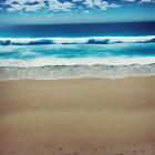 Person walking on sandy beach with blue ocean and cloudy sky