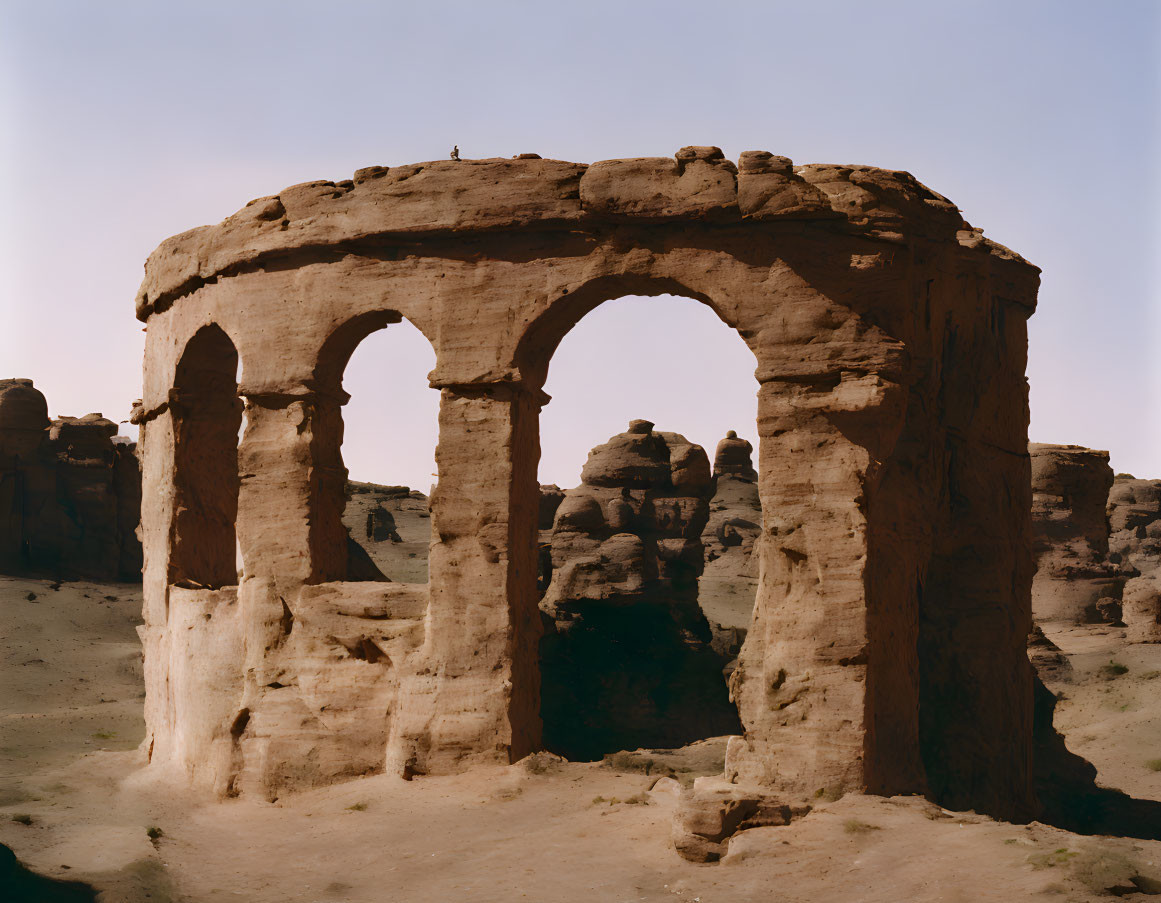 Ancient stone arches among rock formations under clear sky