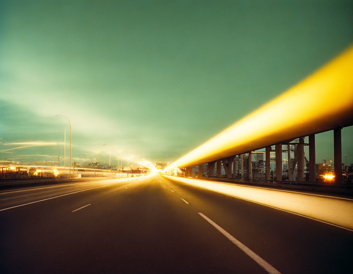 Deserted multi-lane highway at twilight with city skyline and street lights.