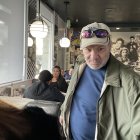 Pensive man in jacket at diner counter with blurred background patrons and hanging lamps