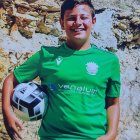 Smiling person in green soccer kit with football and waterfall background