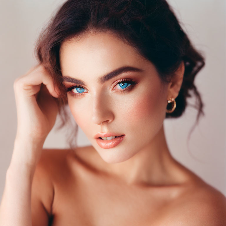 Portrait of woman with blue eyes, subtle makeup, tousled hair, touching temple