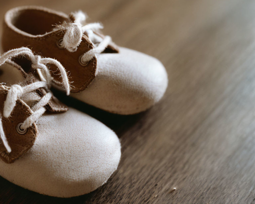 Soft Off-White Baby Shoes with Laces on Wooden Surface