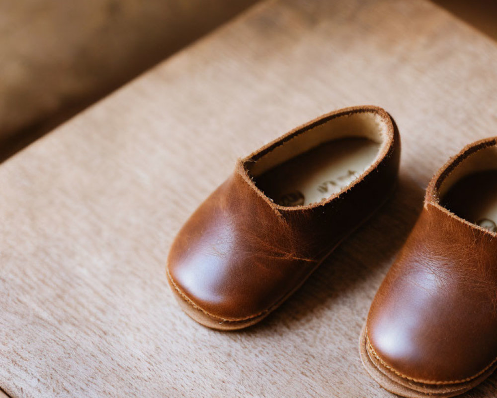 Brown Leather Children's Shoes on Wooden Surface with Soft-focus Background