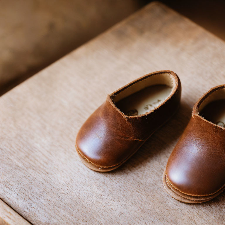 Brown Leather Children's Shoes on Wooden Surface with Soft-focus Background