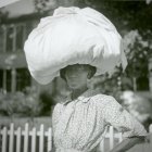 Monochrome image of a woman in a flower-shaped hat and lace blouse