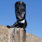 Intricately designed black cowboy boot sculpture on graffiti-adorned structure