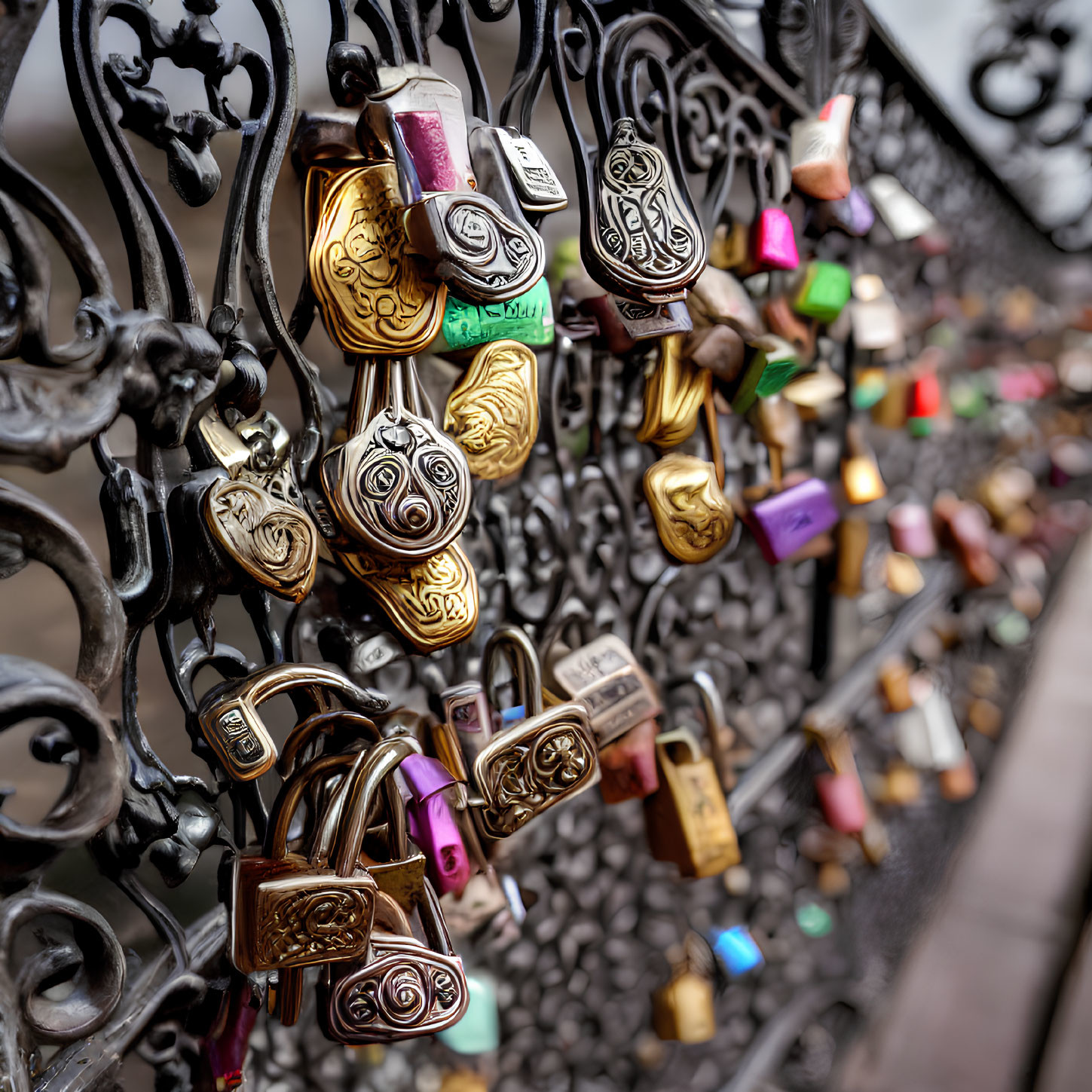 Assorted padlocks on bridge railing with ornate metalwork