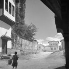 Monochrome illustration of person walking in quaint village under starry night sky