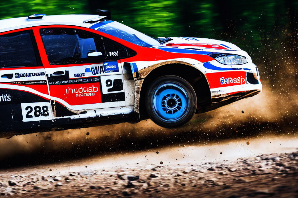 Red and white rally car speeding on dirt track, kicking up dust.