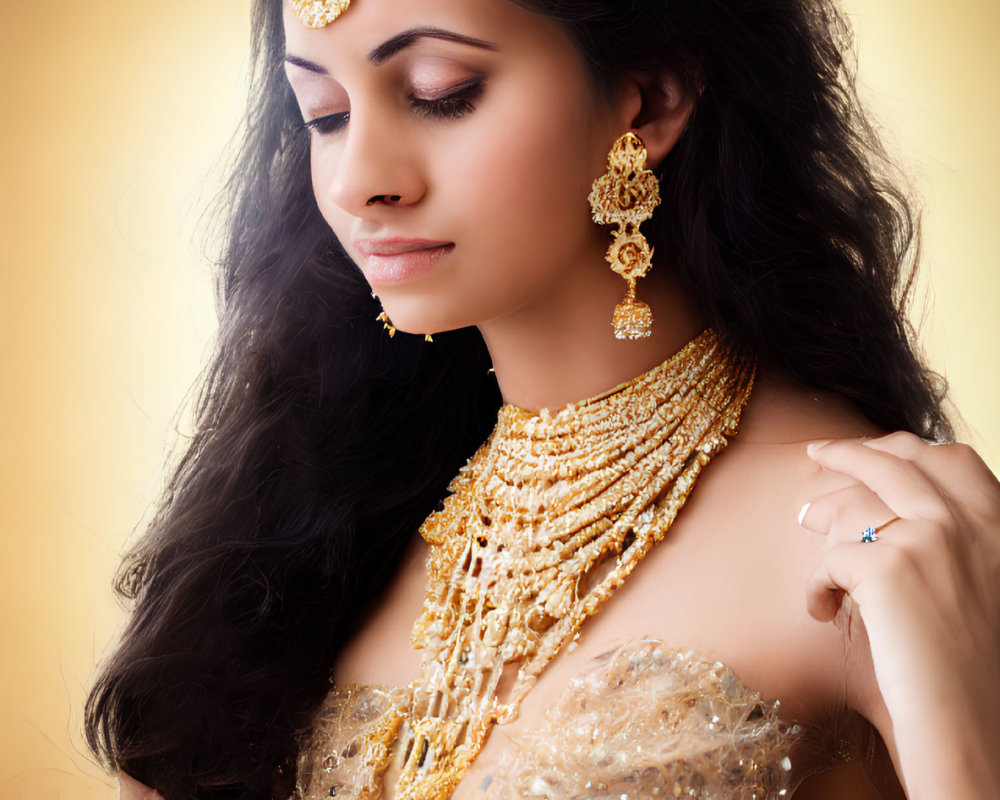 Elaborate gold jewelry on woman against warm backdrop