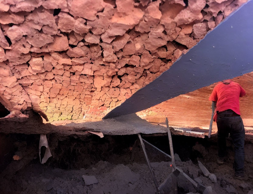 Construction worker installing metal beam under stone brick ceiling