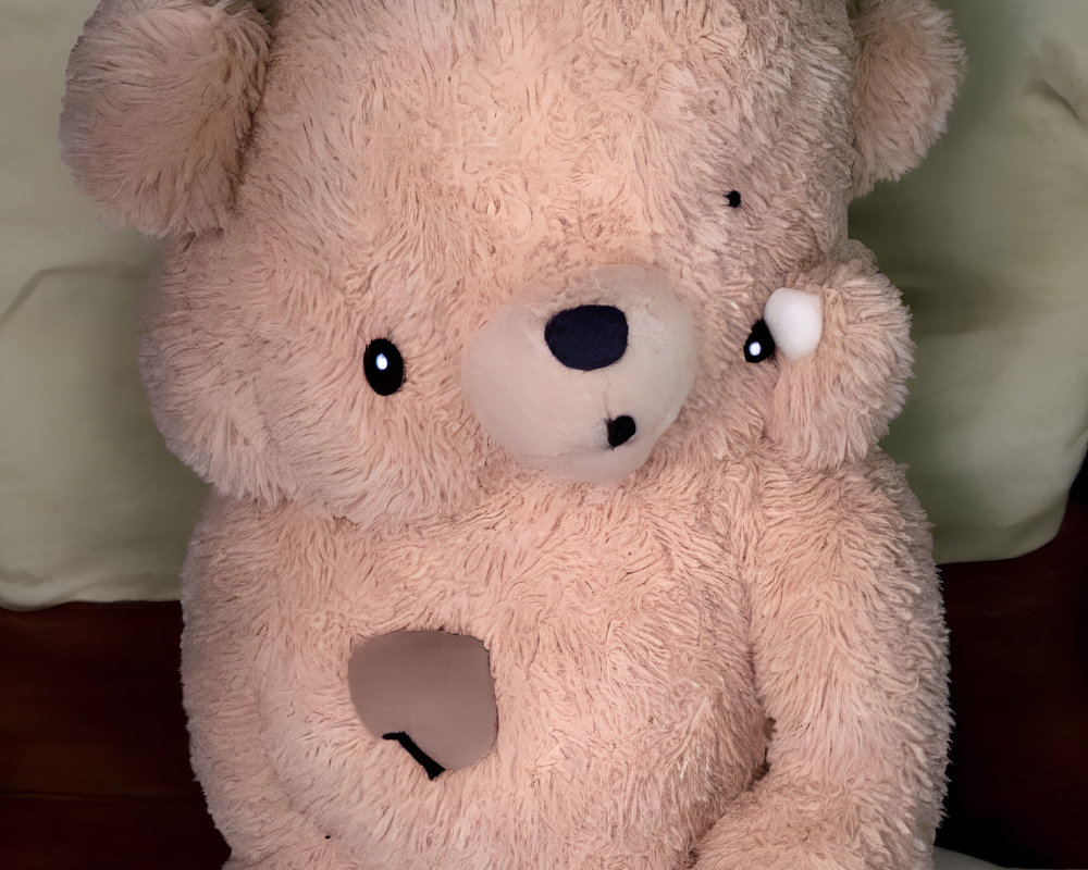 Plush teddy bear with missing eye and heart-shaped hole on chest on green pillow bed