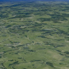 Green Patchwork Landscape with Rolling Hills and Snow-Capped Mountains