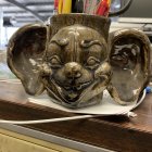 Detailed Demonic Creature Mask with Red Eyes, Teeth, and Horns on Artist's Table