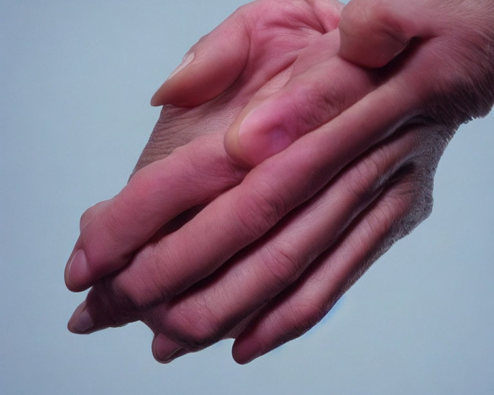 Human hands clasped in togetherness on blue background