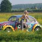 Vibrant surreal landscape with rolling hills, large cactus, woman on colorful car.