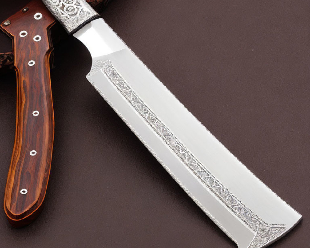 Intricately patterned silver blade on polished wooden handle