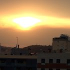 Crowd on ornate balcony at sunset with skyline and spires.