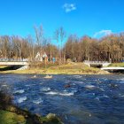 Tranquil river with vibrant flora and cozy cottages among autumn trees