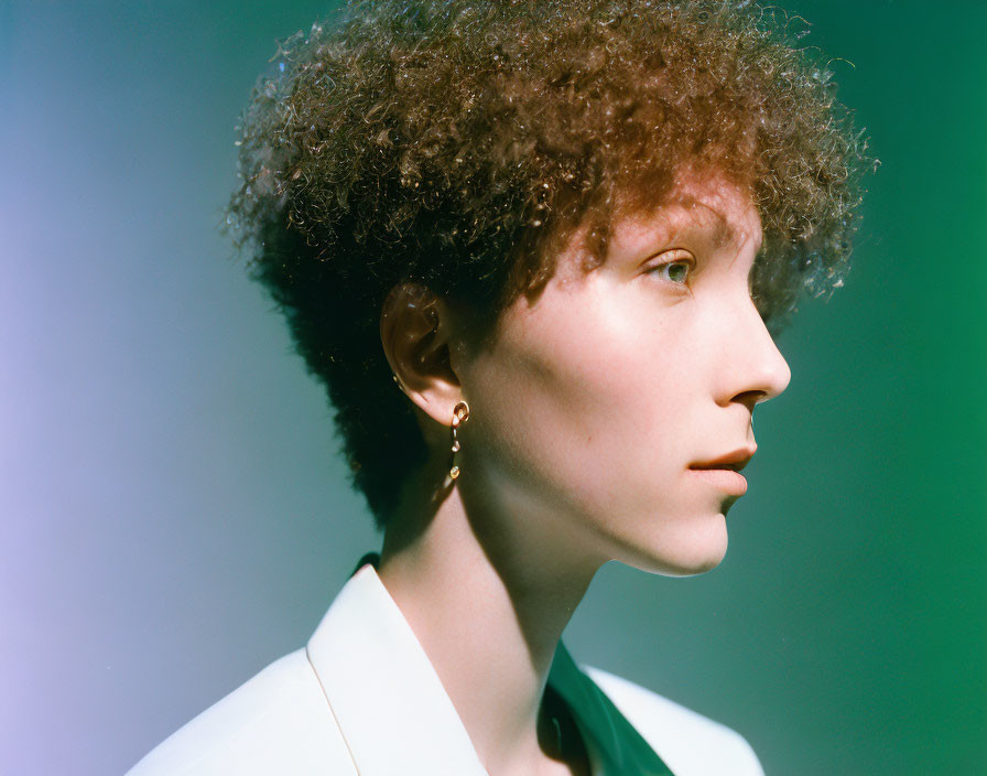 Curly-Haired Person in Hoop Earring & White Blazer on Soft Background