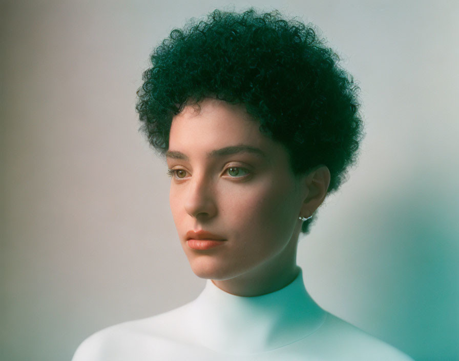 Person with Short Curly Hair and High-Neck Top in Soft Background