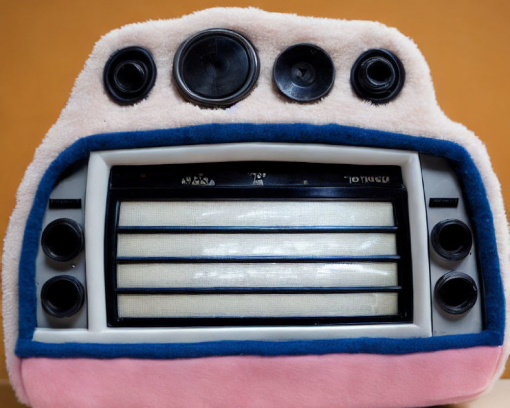 Vintage radio wrapped in pink and white fluffy fabric on orange backdrop