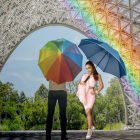 Couple Holding Hands Under Colorful Umbrellas in Wet City Scene