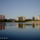 Vibrant waterfront buildings and church spire by calm lake under soft cloudy sky