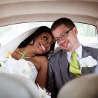 Smiling bride and groom intimate moment in car with bouquet