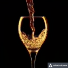 Pouring Golden Liquid into Wine Glass on Dark Background