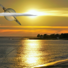 Vivid sunset over wavy sea with boat silhouette, cliffs, and solar eclipse