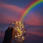 Colorful orbs in glass jar overflow with rainbow stream