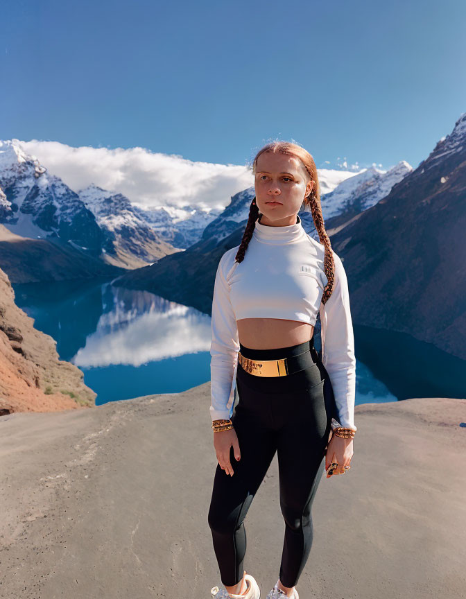 Woman in White Top and Black Leggings on Mountain with Lake and Snow-Capped Peaks