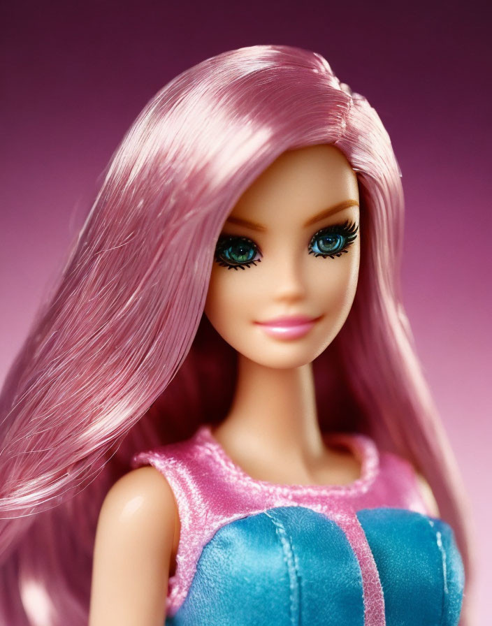 Pink-haired doll with blue eyes and colorful dress on pink background