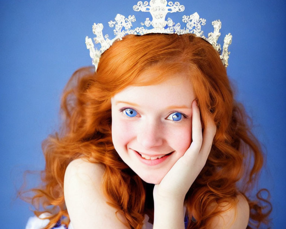 Red-haired woman in tiara smiling on blue background