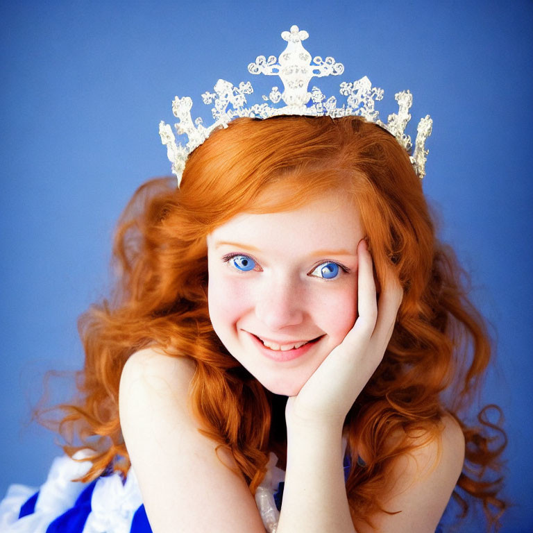 Red-haired woman in tiara smiling on blue background