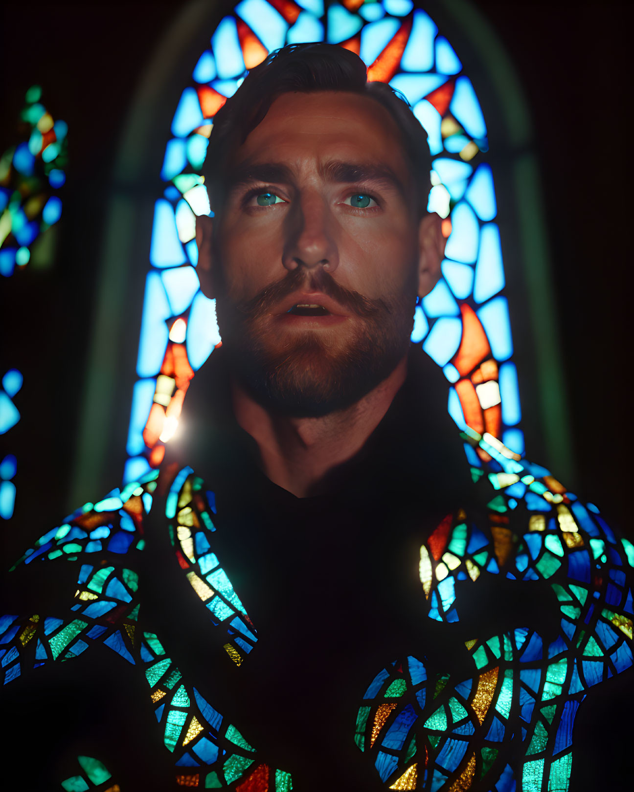 Bearded man looking up under colorful stained glass light